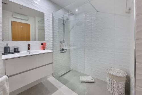 ein weißes Bad mit einem Waschbecken und einer Dusche in der Unterkunft Cozy Corcovada T1 in Albufeira