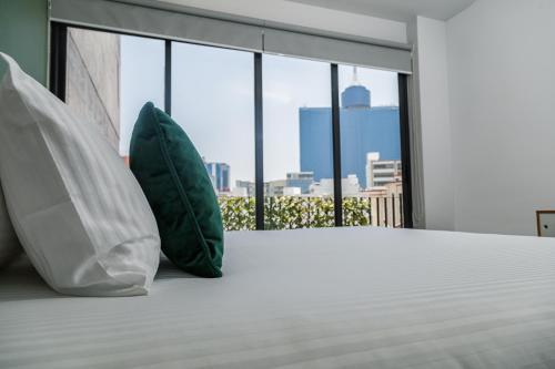 two pillows sitting on a bed in a room with a window at NIU Modern Apartments near WTC & Condesa - Roma Sur in Mexico City