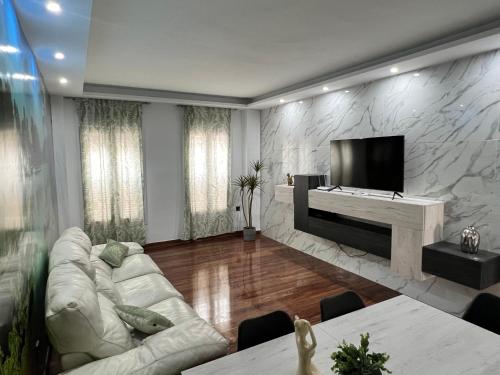 uma sala de estar com um sofá branco e uma televisão de ecrã plano em Ribera house Sevilla em Coria del Río