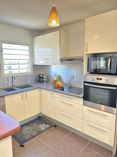 a kitchen with white cabinets and a sink at Wave Coconut Villa in Le Moule