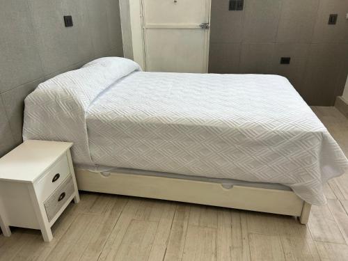 łóżko z białą kołdrą i szafką nocną w obiekcie Rose 5 w mieście Cancún