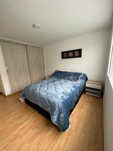 a bedroom with a bed with a blue comforter at Aparta-estudio Ciudad Jardin Norte 202 in Bogotá