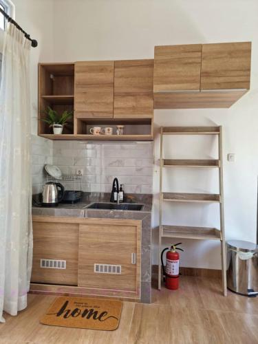 uma cozinha com armários de madeira, um lavatório e uma escada em Rumah Tropis - Lantai 1, single room em Parit