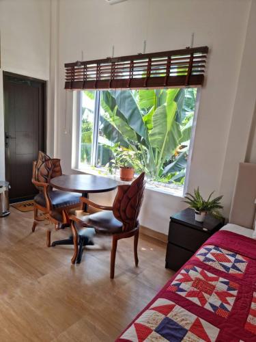 ParitにあるRumah Tropis - Lantai 1, single roomのテーブルと椅子、窓が備わる客室です。
