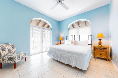 a bedroom with blue walls and a bed and a chair at The Frontier Flat in Key West