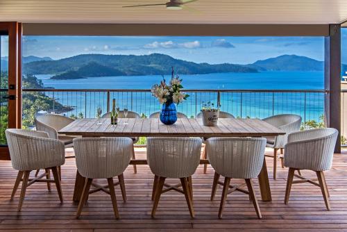 a wooden table and chairs on a deck with a view at Horizons on Hamilton Island by HIHA in Hamilton Island