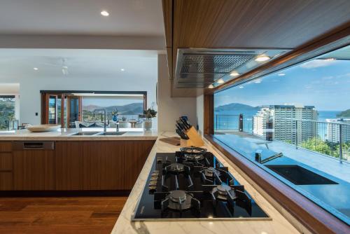 a kitchen with a stove top oven next to a large window at Horizons on Hamilton Island by HIHA in Hamilton Island