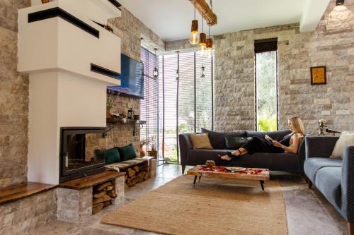 a woman sitting on a couch in a living room with a fireplace at COUNTRYSIDE VILLA in Ulcinj