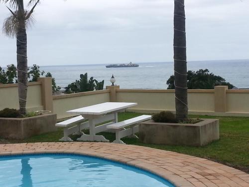a table and a picnic table next to the ocean at The Homestead Margate - South Africa in Margate