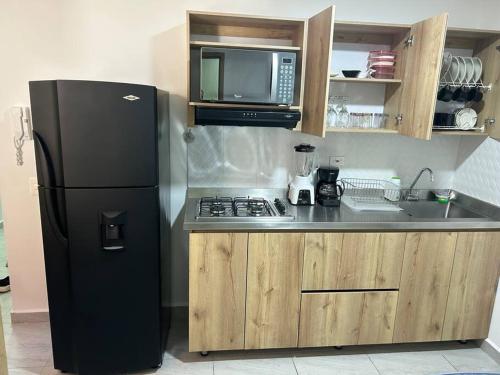 La cuisine est équipée d'un réfrigérateur noir et d'un évier. dans l'établissement Lindo apartamento Medellín zona céntrica, à Medellín