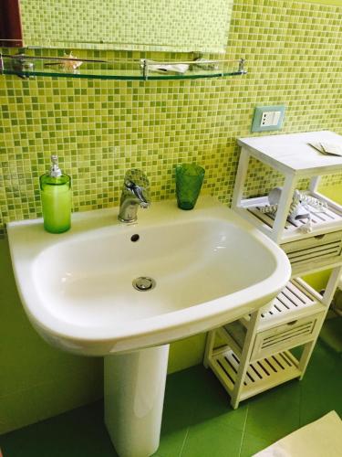 a bathroom sink with two green cups on it at Zahir da Cleo in Castro di Lecce
