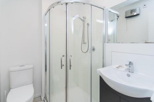 a bathroom with a glass shower and a sink at The Hibernian Studio Apartments - 4 Latter Street in Timaru