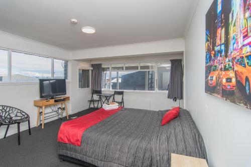 1 dormitorio con 1 cama y TV en The Hibernian Studio Apartments - 4 Latter Street, en Timaru