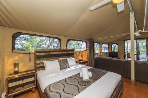 a bedroom in a camper with a bed and windows at Reflections Red Rock - Holiday Park in Red Rock