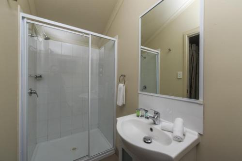 a white bathroom with a shower and a sink at Reflections Red Rock - Holiday Park in Red Rock