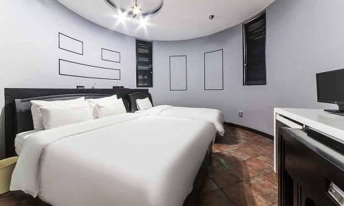 a bedroom with two large white beds and a tv at Paju Picasso in Paju