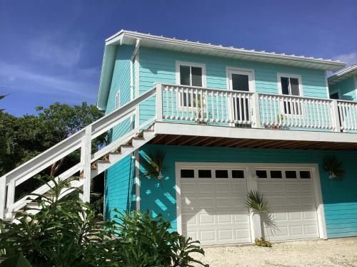a blue house with a balcony and a garage at Flipper Refuge cottage in Governorʼs Harbour