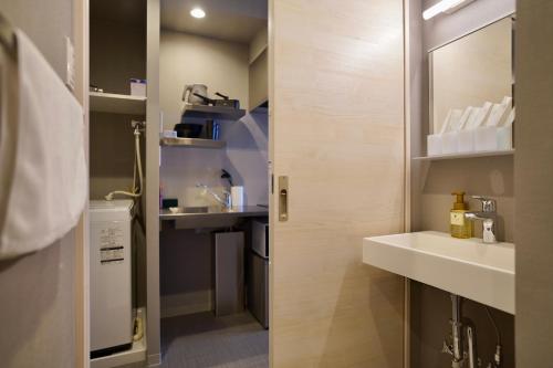 La salle de bains est pourvue d'un lavabo et d'un miroir. dans l'établissement Apartment Hotel 11 Namba Minami Shin-Imamiya, à Osaka