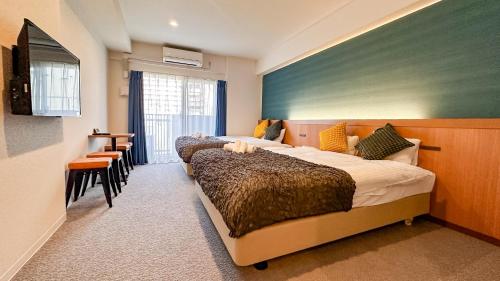 a hotel room with two beds and a table and chairs at Apartment Hotel 11 Namba Minami Shinimamiya in Osaka