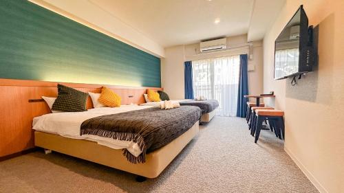 a hotel room with two beds and a flat screen tv at Apartment Hotel 11 Namba Minami Shin-Imamiya in Osaka