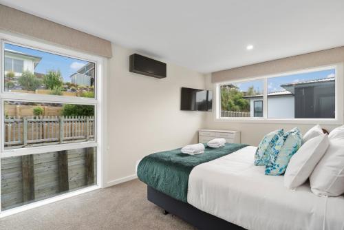 a bedroom with a bed and two large windows at Sanctuary on the Grove in Taupo