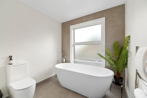 a white bathroom with a toilet and a window at Sanctuary on the Grove in Taupo