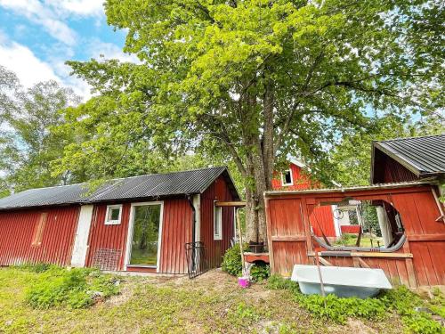 a red house with a tree and a boat next to it at 4 person holiday home in FURUBY-By Traum in Fagereke
