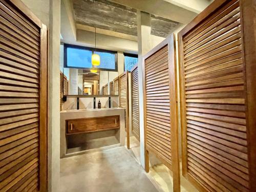 baño con paredes de madera, lavabo y espejo en Nectar Hotel, Cafe, Cowork - Adults Only, en Puerto Escondido