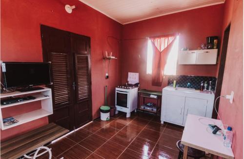 a kitchen with red walls and a television and a table at Sobrado do Eduardo in Barra Grande