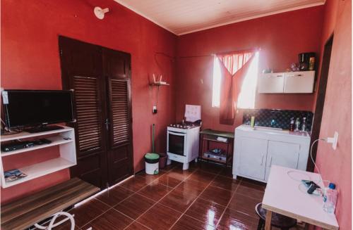 une cuisine avec des murs rouges et une télévision et une table dans l'établissement Sobrado do Eduardo, à Barra Grande