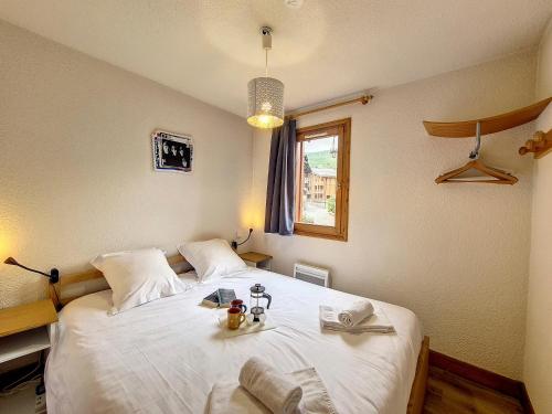 - une chambre dotée d'un grand lit blanc avec deux poupées dans l'établissement Charmant Appartement 3 Pièces - Balcon, Proche Pistes et Commerces - FR-1-344-1067, à Saint-Martin-de-Belleville