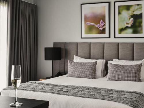 1 dormitorio con 1 cama y 1 copa de vino en Marnong Estate en Craigieburn