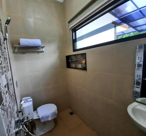 a bathroom with a toilet and a sink and a window at Umah Karet Homestay in Magelang