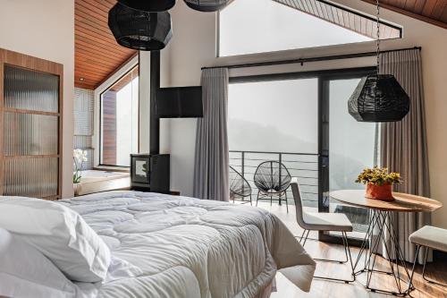 ein Schlafzimmer mit einem großen Bett, einem Tisch und Stühlen in der Unterkunft Refúgio Galli in Encantado