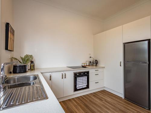 a kitchen with white cabinets and a stainless steel refrigerator at Rata Retreat - Ohakune Holiday Home in Ohakune