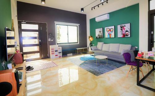 a living room with a couch and a green wall at Sofa Potato Homestay in Magong