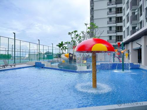 a pool with a red and yellow umbrella in the water at Bali Residences Sea View Suites Melaka in Melaka