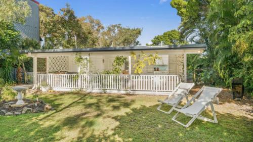 a backyard with two chairs and a white fence at Magnolia Cottage in Woorim