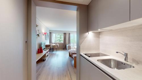 a kitchen with a sink and a living room at Abitaziun Europa 302 - Champfèr in Champfer