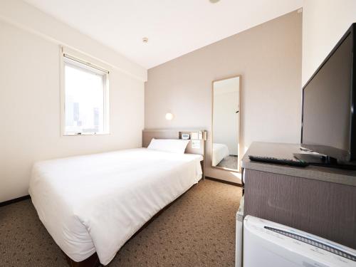 a bedroom with a white bed and a flat screen tv at Super Hotel Tokyo Nihombashi Mitsukoshimae in Tokyo