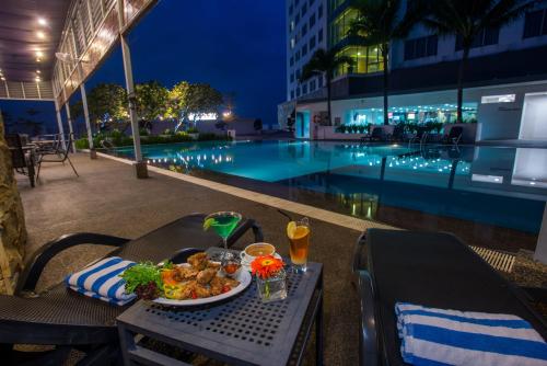 a table with a plate of food next to a pool at Premiere Hotel in Klang