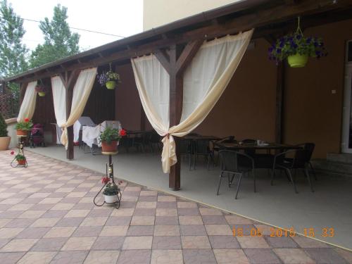 eine Terrasse mit Tischen und Stühlen sowie weißen Vorhängen in der Unterkunft Pensiunea Lari in Baile Unu Mai