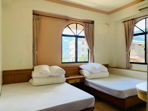 two beds in a room with two windows at Yong Li Hotel in Gukeng