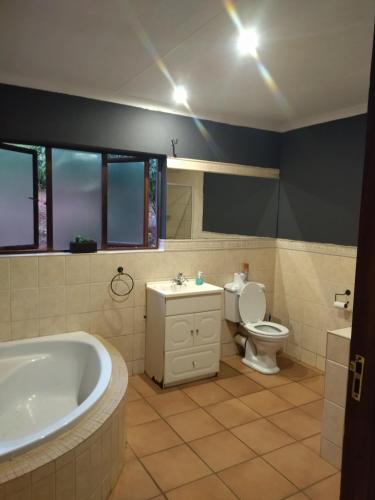 a bathroom with a tub and a toilet and a sink at Patogeng Self Catering - Da Gama Dam view in White River
