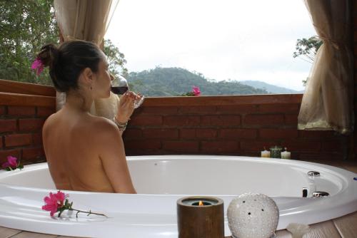 een vrouw in een bad die een glas wijn drinkt bij Chalé Samasati in Visconde De Maua