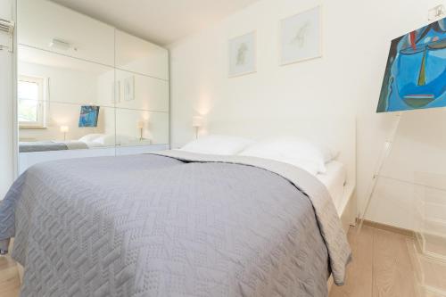 a white bedroom with a large bed and a mirror at Haus Dieksee Holm Seeromantik in Malente