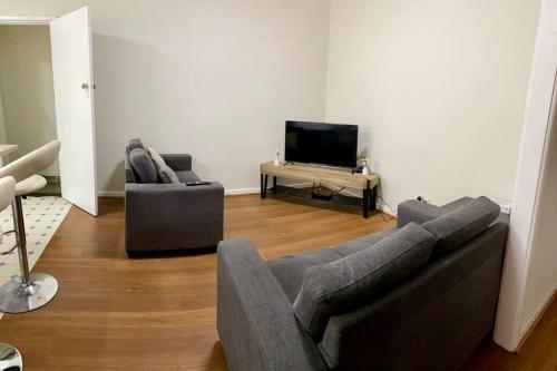 sala de estar con sofá, 2 sillas y TV en 3 Bedroom House, en Merredin