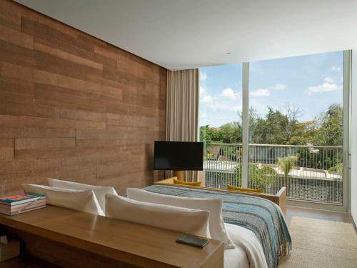 a bedroom with a bed and a large window at Potato Head Suites & Studios in Seminyak