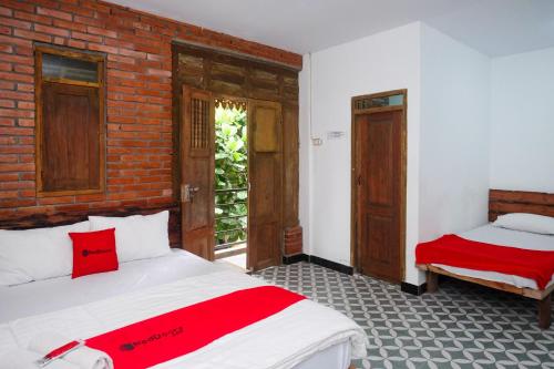 - une chambre avec 2 lits et un mur en briques dans l'établissement RedDoorz Syariah near Akmil Magelang, à Magelang