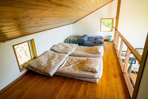 sala de estar con 2 camas y escalera en 野尻湖の絶景を楽しむ、貸切サウナ付き一軒家 Anoie（あの家）, en Shinano